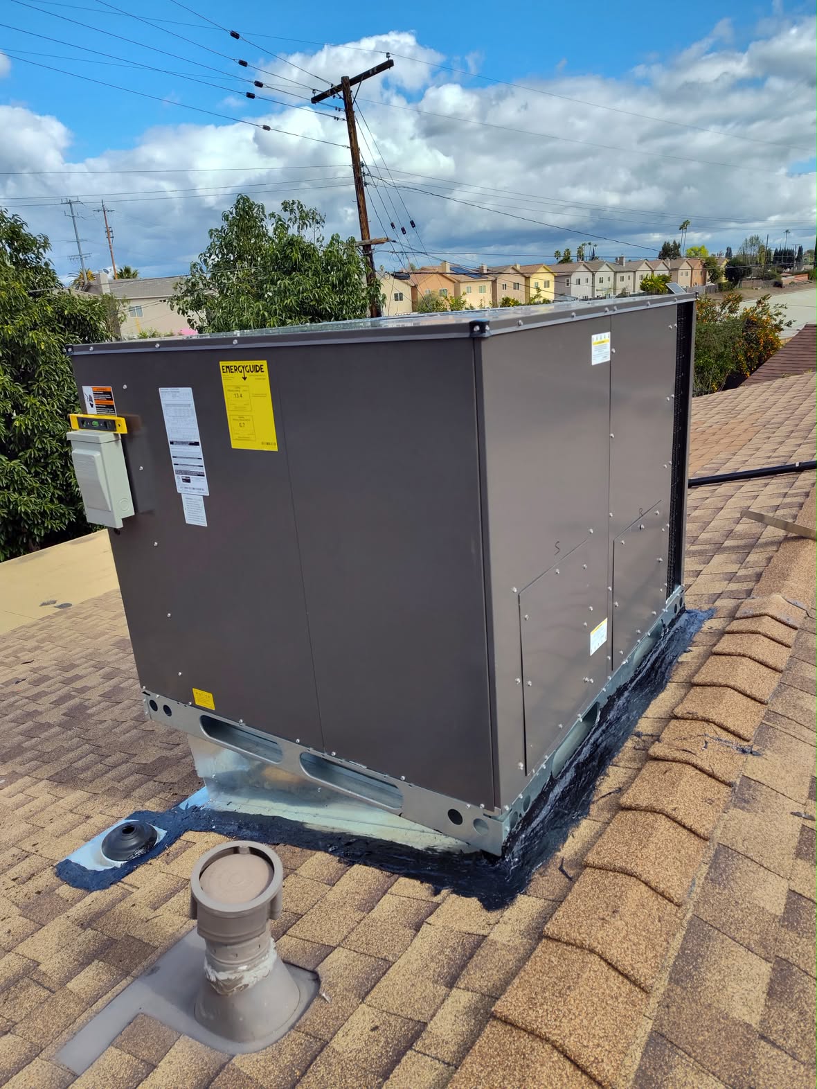 Rooftop package unit set and sealed on a sloped shingle roof